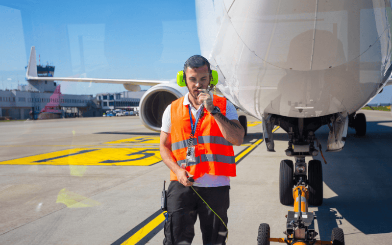 Aircraft worker towing system at the airport. Towing hook attached to plane nose. Man talking with pilot.