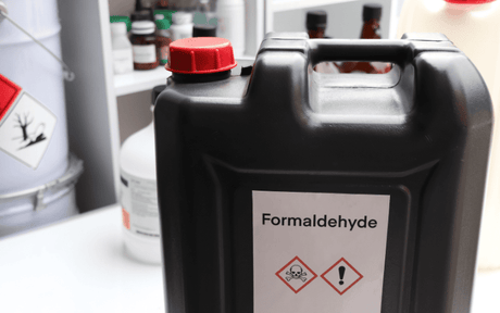 Container labeled 'Formaldehyde' with hazard symbols on a laboratory counter.