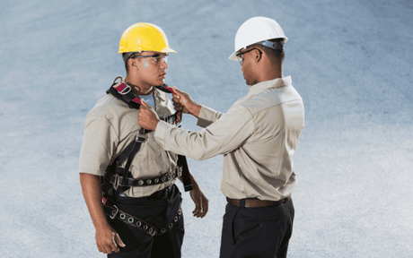 One worker inspecting another's harness.