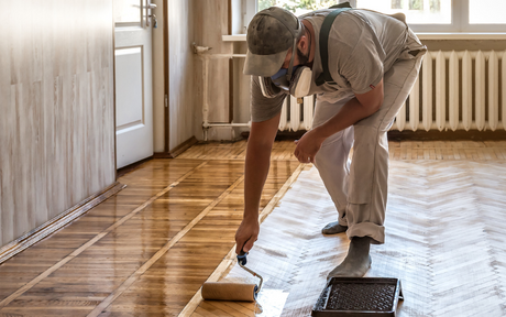 Worker lacquering parquet floors while wearing a half mask respirator for respiratory protection.