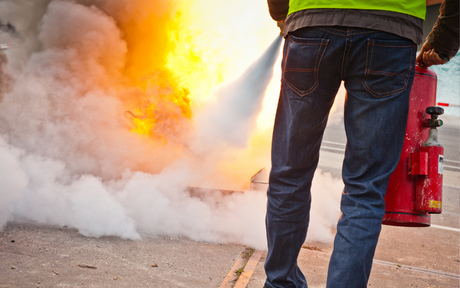 Person puts out fire with fire extinguisher.