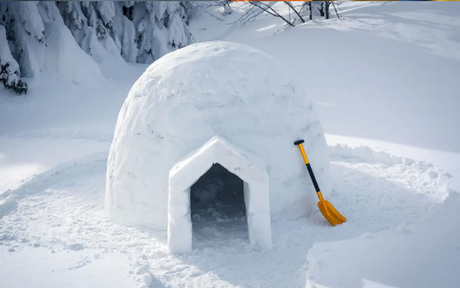 Igloo with a snow shovel propped up against it.