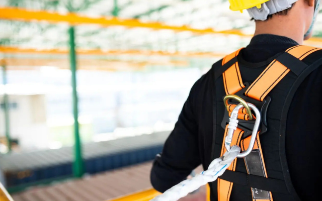 Worker wears safety harness and lanyard.