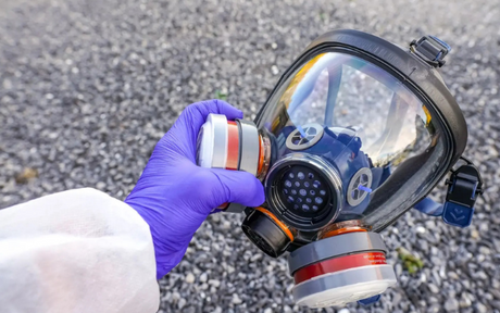 Worker hold a full-face respirator.