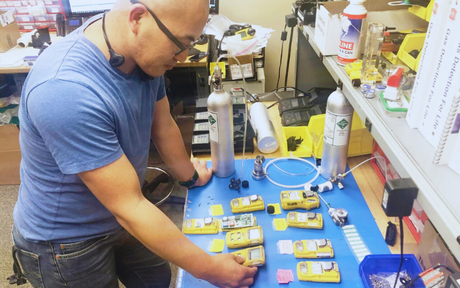 Technician assembling yellow electronic components at workbench.