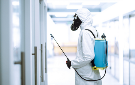 Worker using vaporized hydrogen peroxide (VPH) to disinfect workspace.