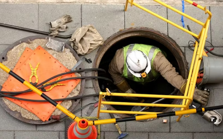 Worker inside confined space manhole.