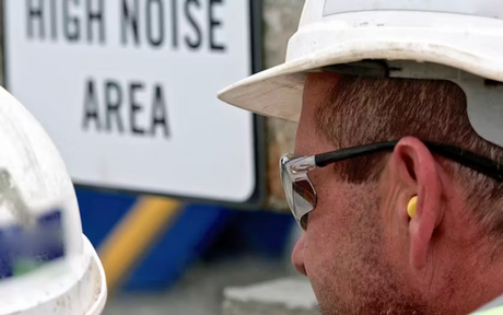 Worker wearing earplugs at high noise jobsite.