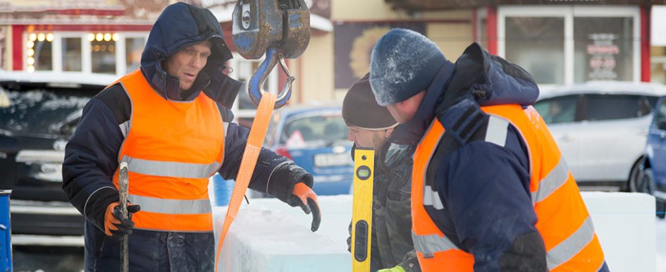 Workers bundled up in the snow wearing safety gloves and winter workwear.