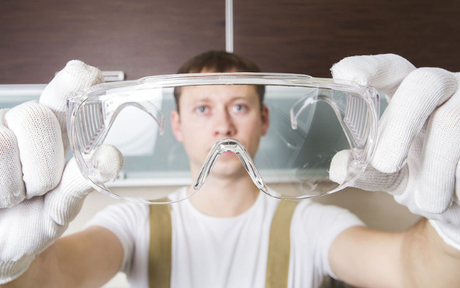 Worker holds up safety glasses.