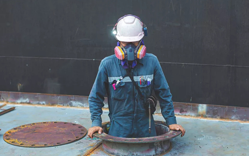 Worker entering a confined space manhole.