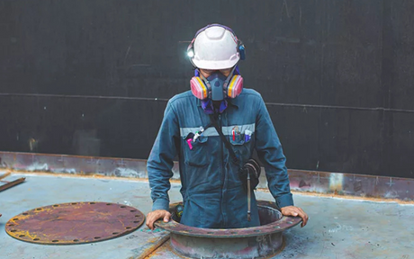 Worker entering a confined space manhole.