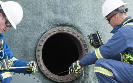 Confined space workers testing gas with gas detector