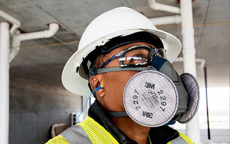 Construction worker wearing respirator, hard hat and glasses.