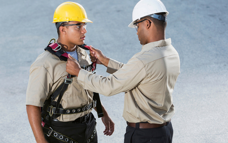 This fall safety inspection includes workers looking over a harness.