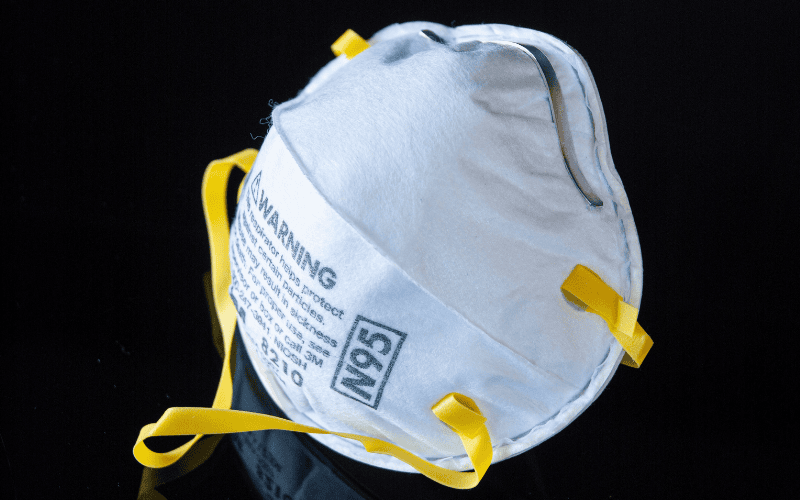 N95 respirator mask with yellow straps and black background.