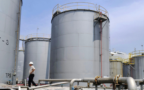 Worker walking outside of oil tanks.