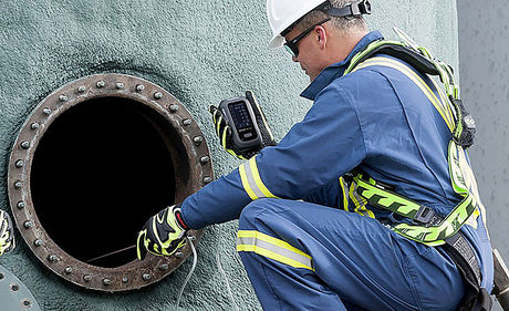 Worker testing for hazardous gases in confined space.