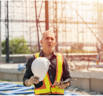 Tired, fatigued worker wearing high vest in a construction site.