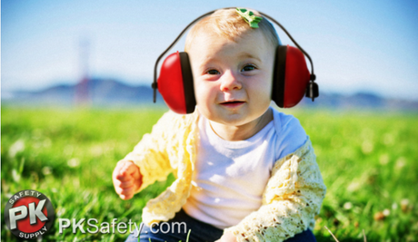 Baby wearing ear muffs in a field.