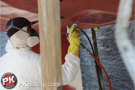 Man wearing respirator, hazmat suit, and gloves painting the bottom of a boat.