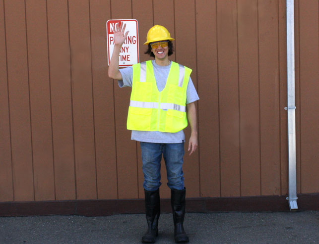 Man wearing helmet, hi-vis vest and boots waving.