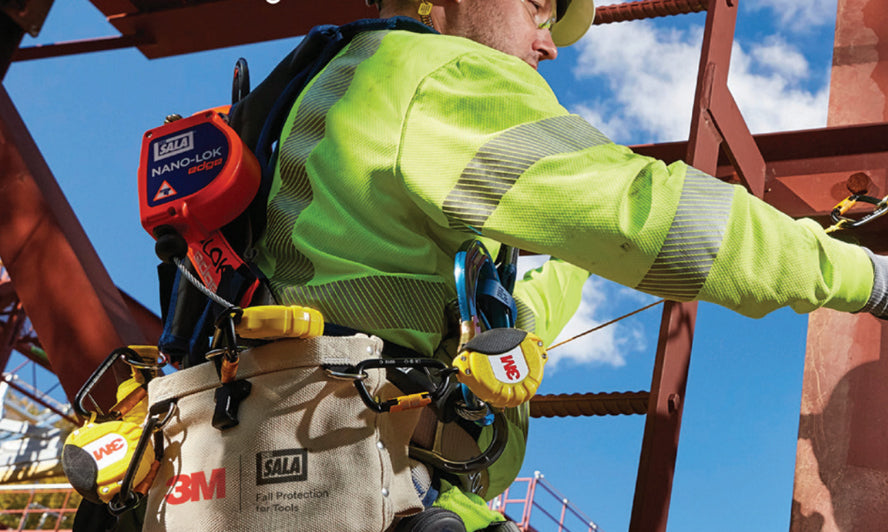 A worker working at height has tools connected and securely bagged.