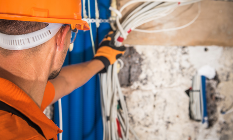 Worker inspects wiring for potential electrical hazards.