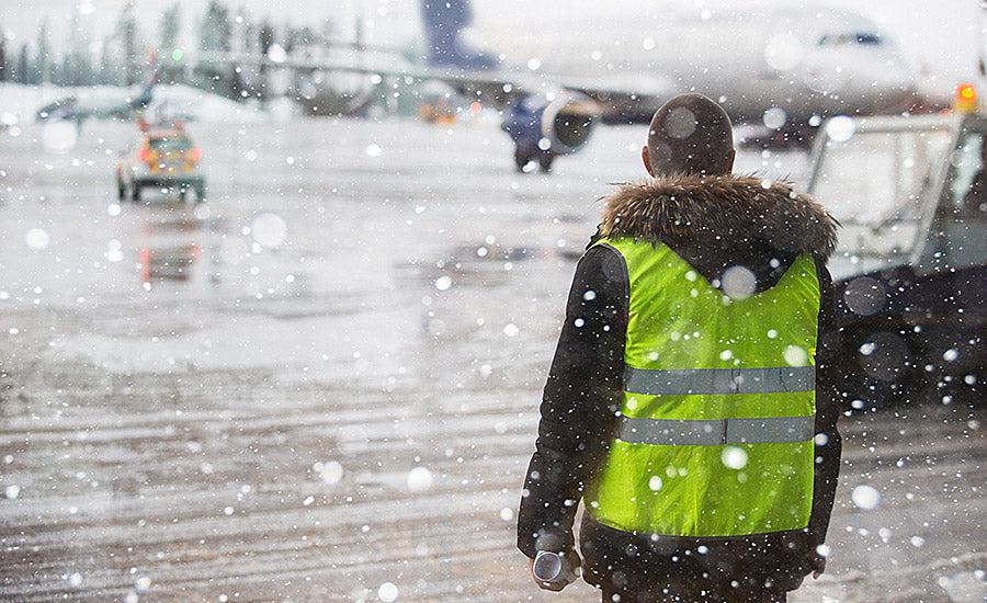 Worker dressed in layers while snow falls at jobsite.