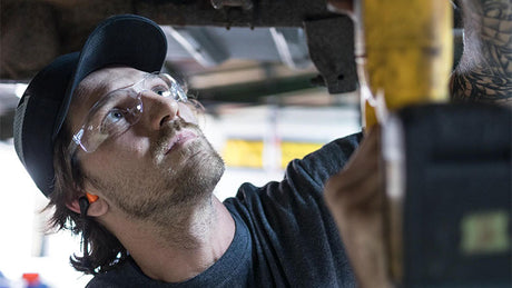 Worker wears safety glasses while working on a vehicle.