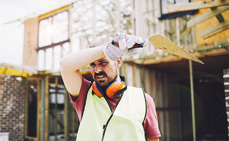 Worker wiping sweat of head while on the jobsite.