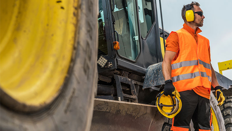 A construction worker in PPE looks towards the jobsite.