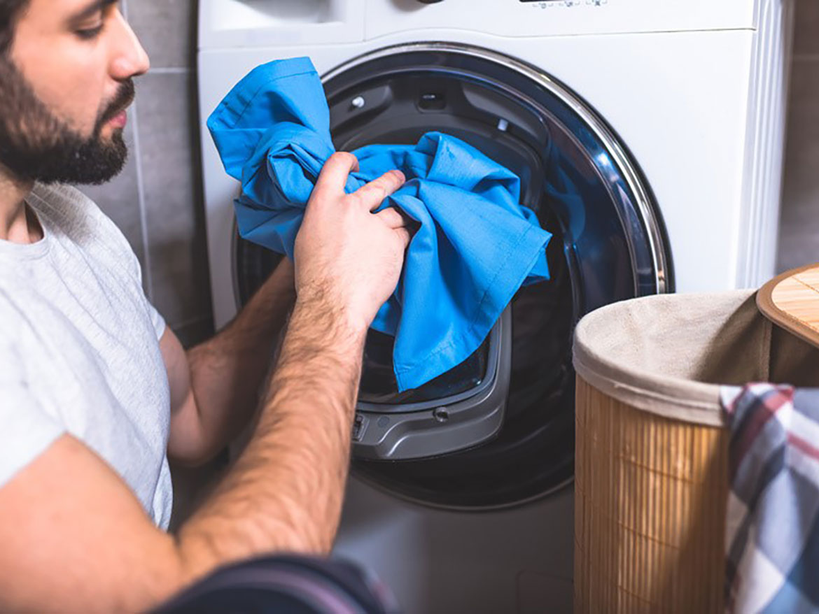 Worker putting workwear in the washing machine.