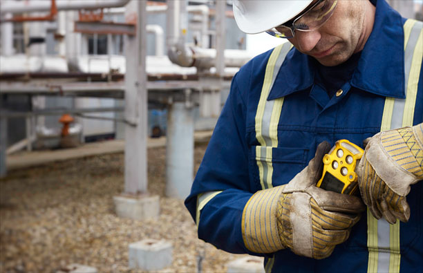 Oil and gas worker looks at gas detector he's wearing on his chest.