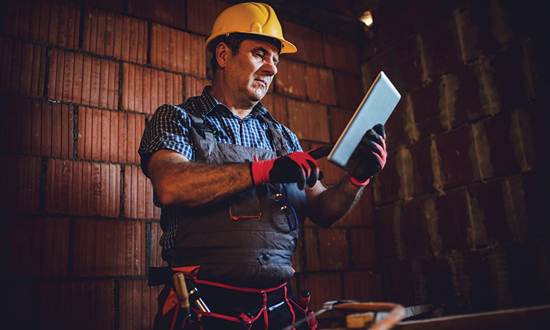 Worker wearing touchscreen gloves while looking at tablet.