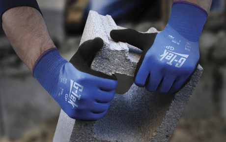 Worker wearing blue safety gloves while handling with concrete block