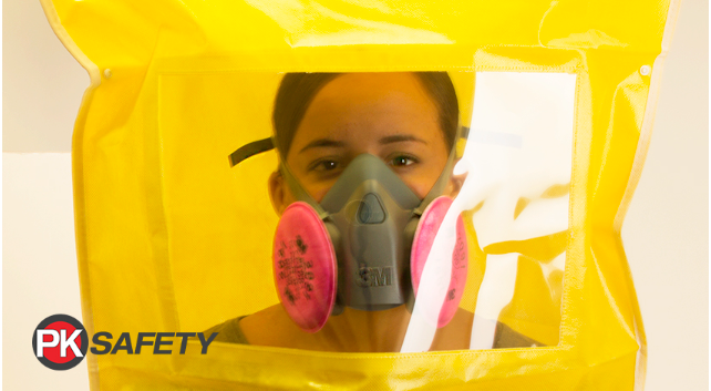 Woman wearing a half-mask respirator with yellow fit test bag covering head.
