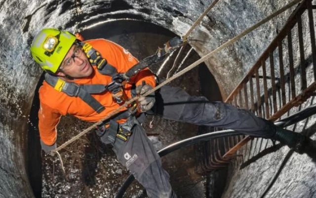 Worker in confined space wearing safety harness.