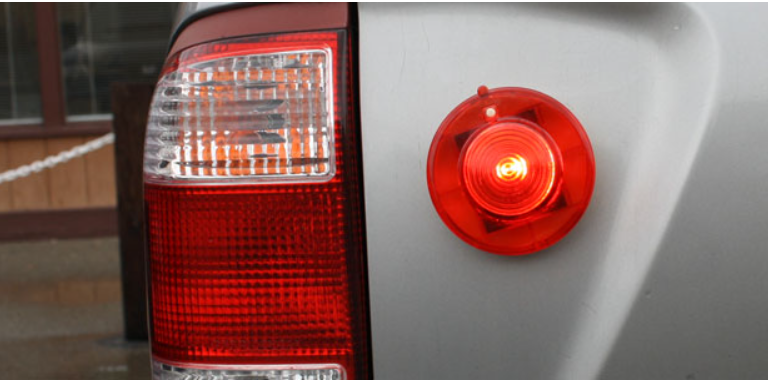 Red Aervoe Rechargeable Super LED light on back of grey vehicle.
