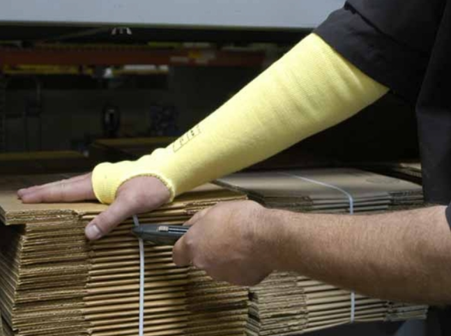 Man wearing Memphis 9378T 18” knit sleeves using a box cutter on a stack of folded boxes.