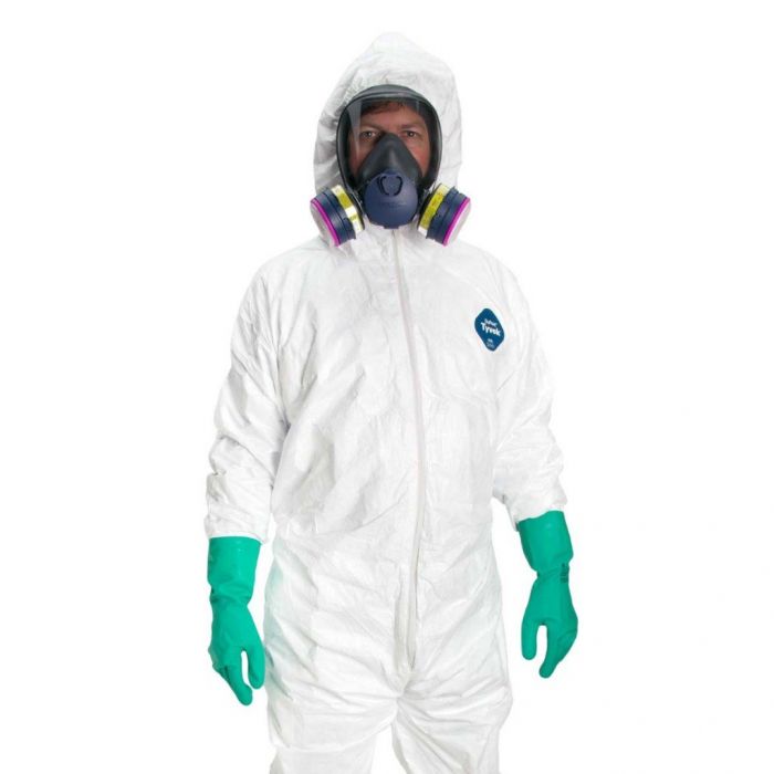 Man wears hazmat suit with full-face respirator and green gloves on white background.
