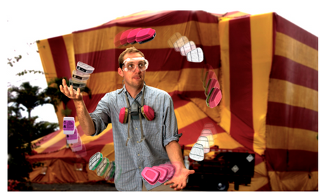 Man wearing safety goggles juggling respirator filters standing in front of tented building..