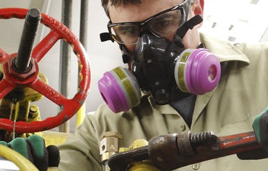 Worker wears half mask respirator while working in facility.