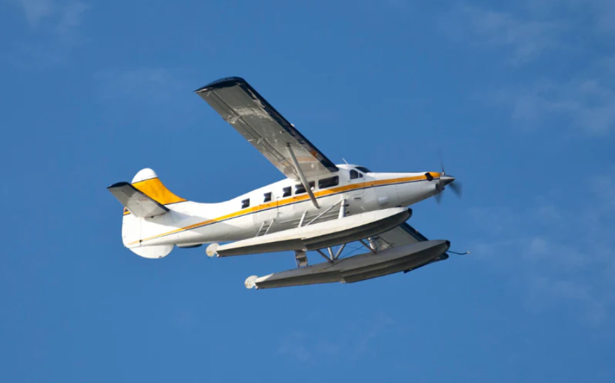 Seaplane flying with blue sky behind it.