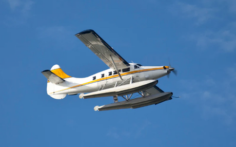 Seaplane flying with blue sky behind it.
