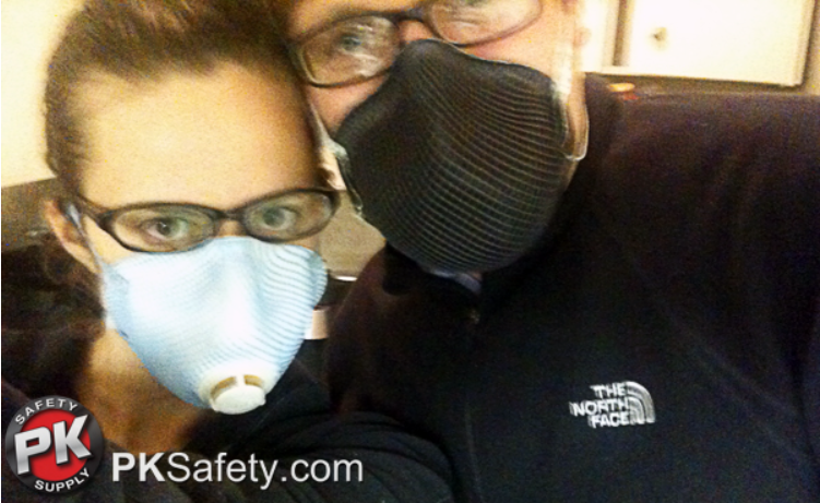 Blurry image of man and woman wearing glasses and respirators.