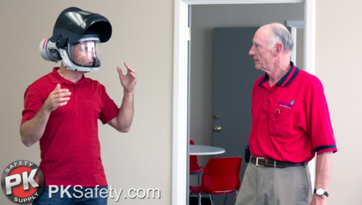 One man wears a Pureflo helmet while talking to another man.
