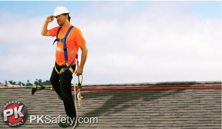 Guy wears harness and hard hat while standing on roof.