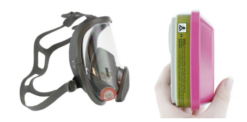 Side view of full-face respirator mask and hand holding a respirator filter on white background.