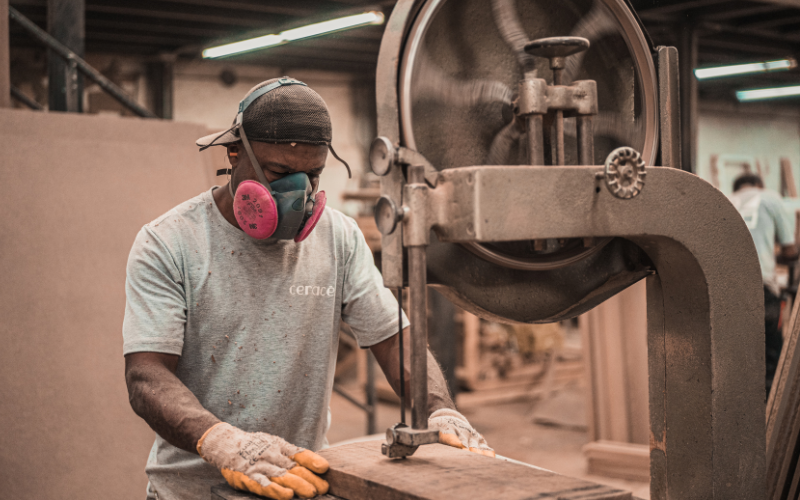 Man wearing half mask respirator using a machine to cut wood.